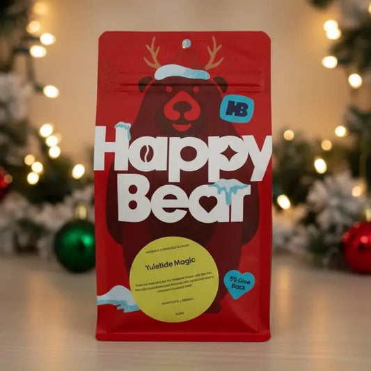 Red 'Happy Bear' package with a Christmas tree and ornaments in the background